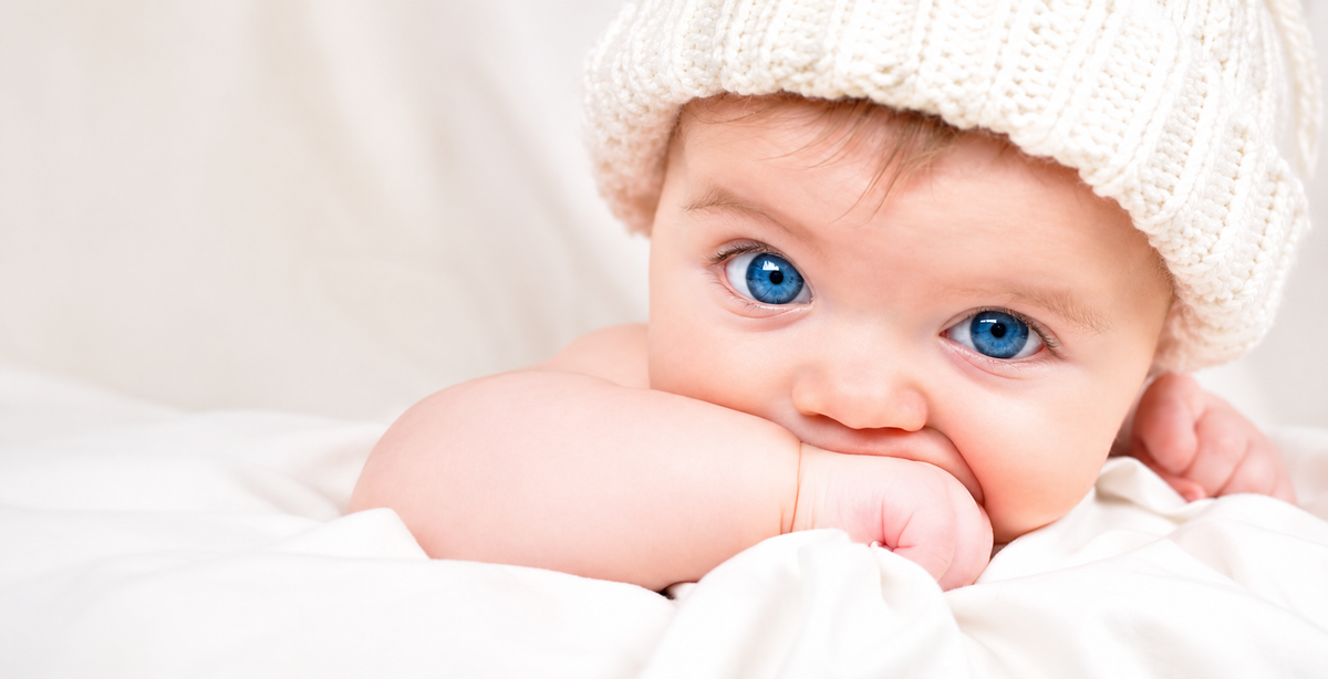 Bébé fille aux yeux bleus avec bonnet en laine crème – nouveau-né