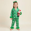 enfant vêtue d’un pyjama de noël vert sapin tenant une peluche du père noël