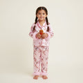 Enfant en pyjama de Noël rose à motifs pain d’épices et sapins avec bordures en fausse fourrure rose