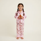 Enfant en pyjama de Noël rose à motifs pain d’épices et sapins avec bordures en fausse fourrure rose