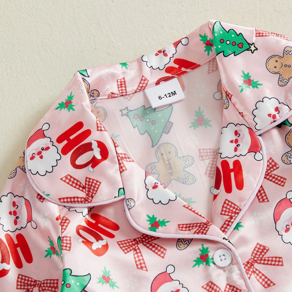 Détail du col d’un pyjama de Noël rose avec motifs Ho Ho Ho, sapins et bonhommes pain d’épices