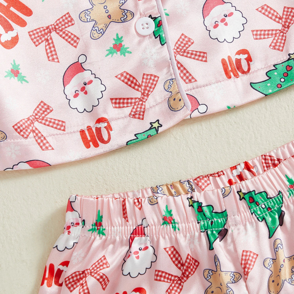 Détail du pantalon de pyjama de Noël enfant avec motifs Pères Noël, sapins et rubans rouges