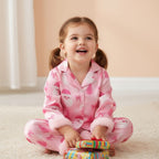 Petite fille souriante en pyjama de Noël rose tenant des cadeaux colorés