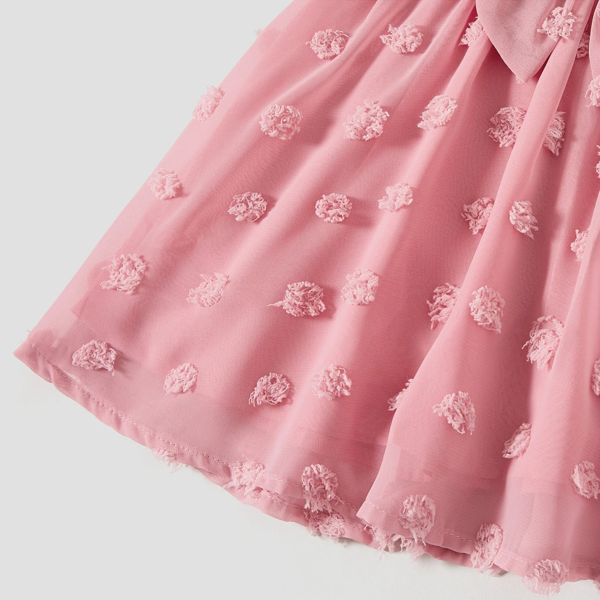 Détail de l’ourlet fluide et du tissu léger de la robe rose pour fille