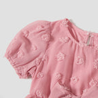 Détail du tissu à pois en relief et des manches bouffantes de la robe rose