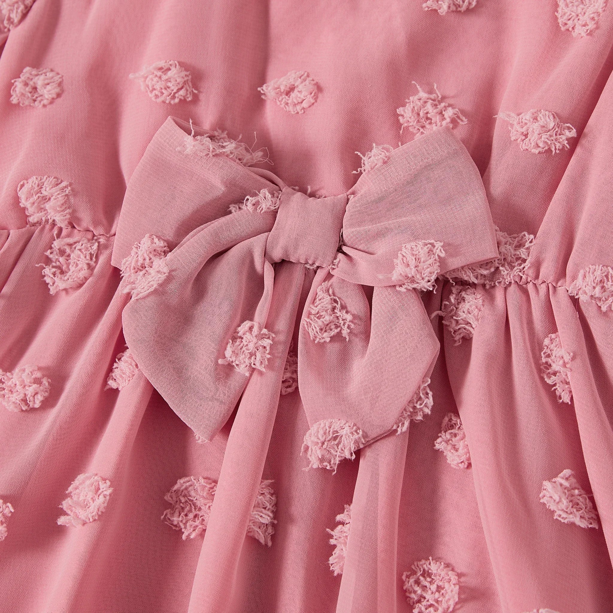 Gros plan sur le nœud décoratif à la taille de la robe rose mère et fille