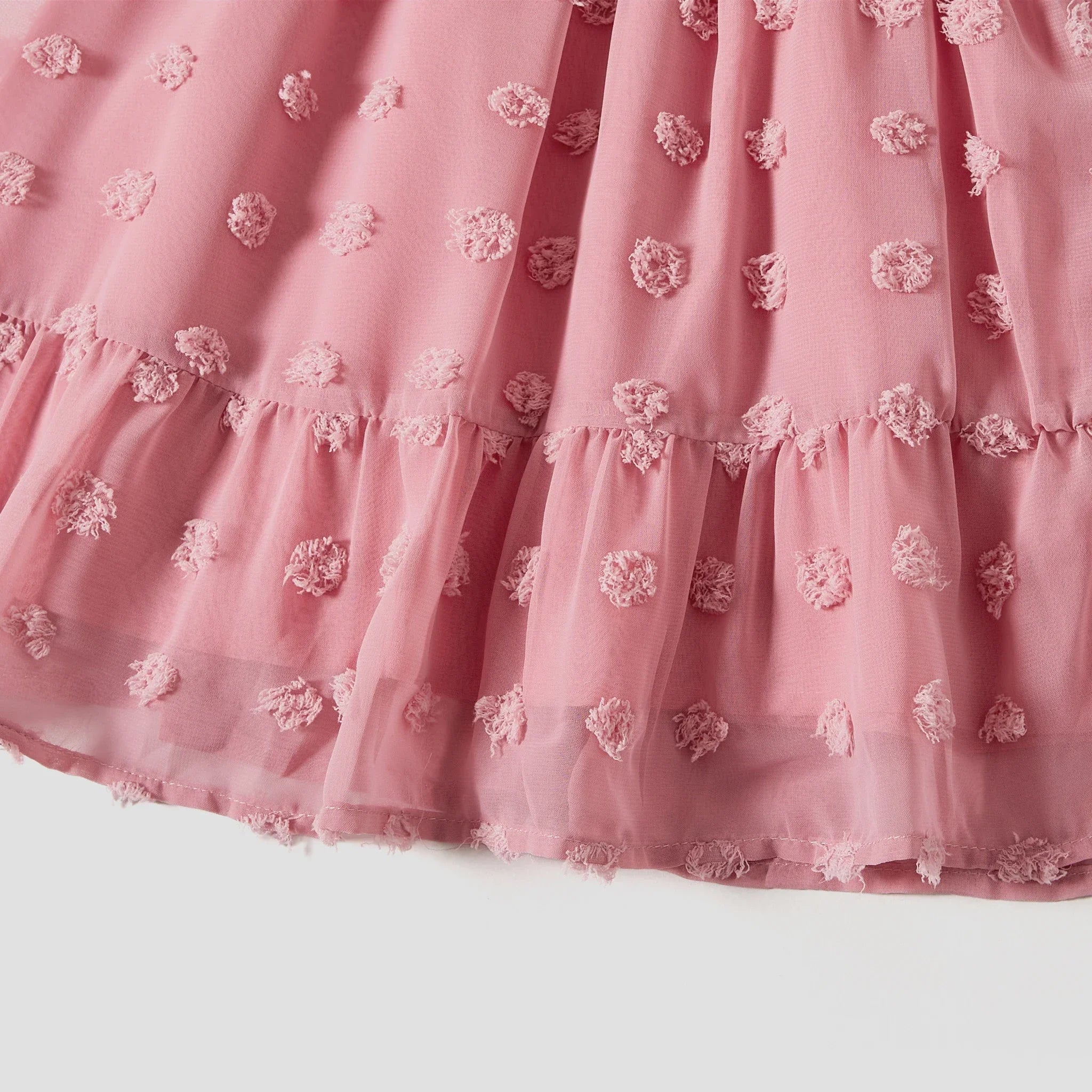 Zoom sur le volant plissé de la robe rose fluide en mousseline