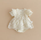 Barboteuse de cérémonie pour bébé couleur ivoire avec bustier en dentelle florale, boutons perles et manches bouffantes festonnées