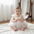 Bébé assis portant la version blanche de la barboteuse ange idéale pour un shooting photo