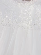Gros plan sur les motifs floraux complexes en dentelle blanche de la robe de cérémonie Céleste