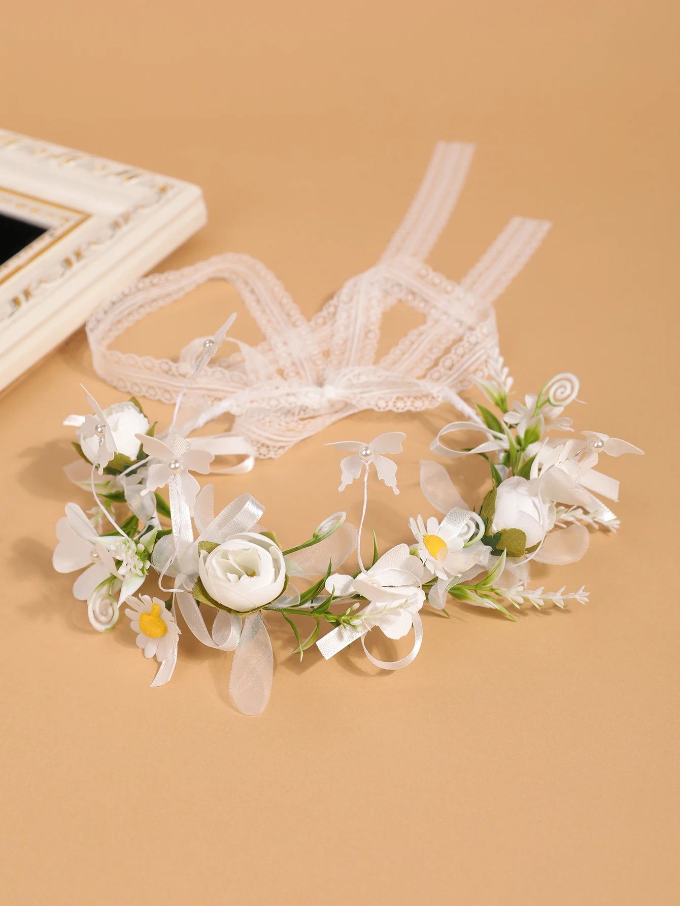 Zoom sur les longs rubans de dentelle et de satin blanc permettant d'ajuster la couronne de fleurs à l'arrière
