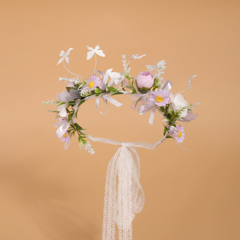 Détail d'une couronne florale bohème pour enfant montrant le mélange de feuillage vert et de papillons légers