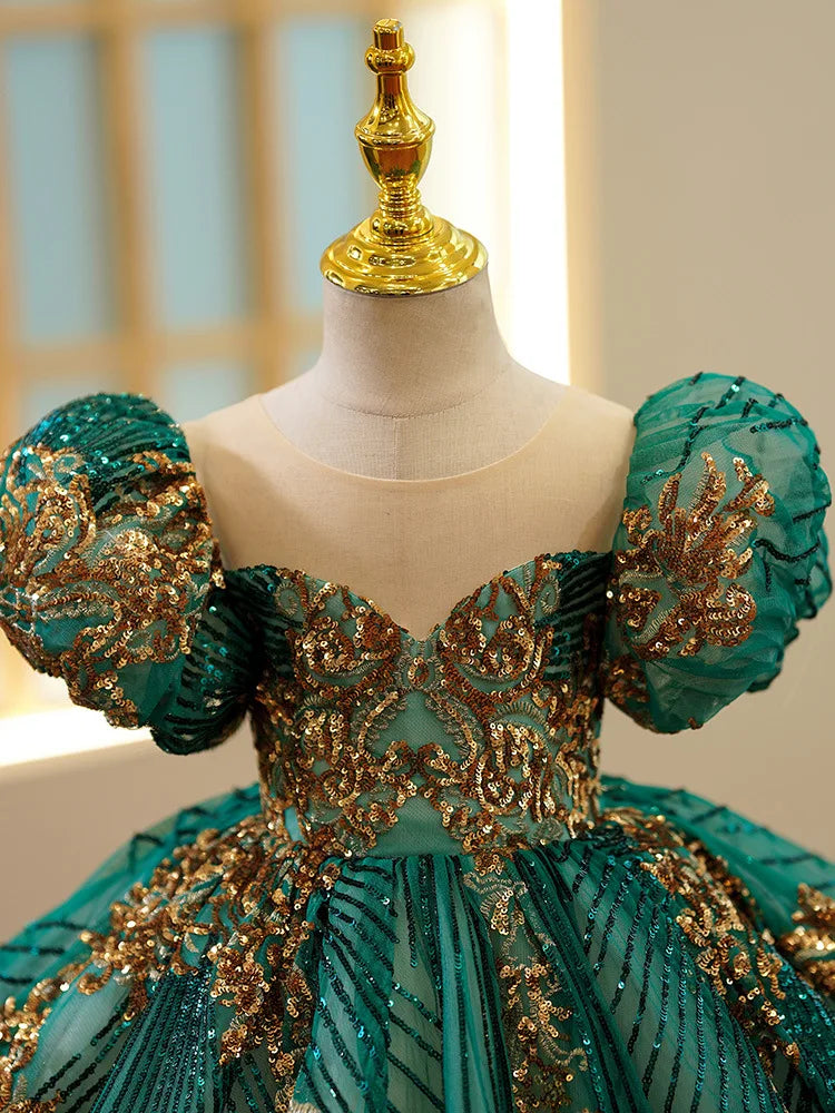 Gros plan sur les détails des broderies au fil d'or et les finitions de la robe de prestige verte