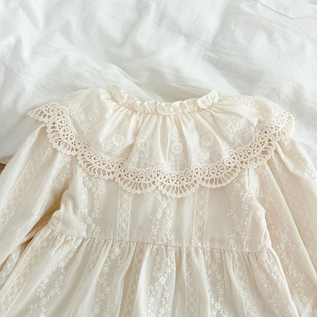 Détail du col claudine à volants avec broderie anglaise raffinée sur coton beige