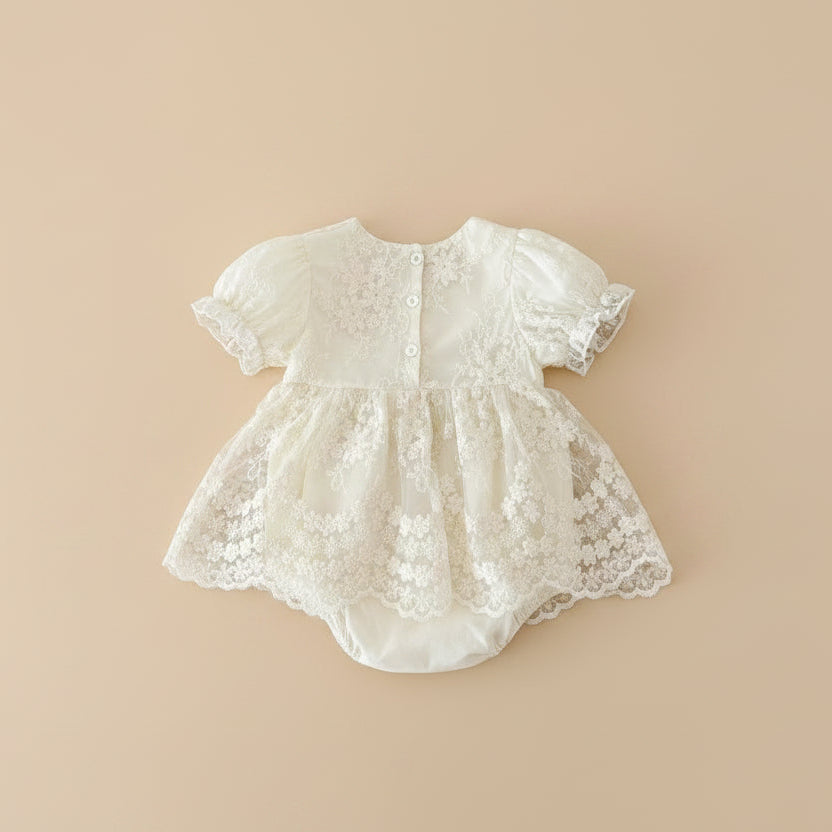 Gros plan sur les détails de la barboteuse Juliette montrant la dentelle complexe et les boutons perles nacrés avec sertissage doré