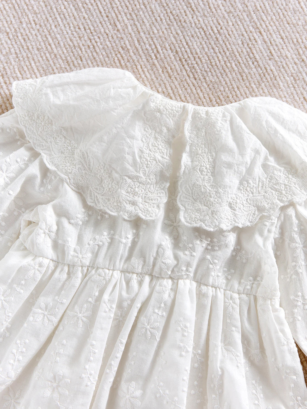 Détail du col Claudine en dentelle anglaise et broderies d'une barboteuse de baptême.