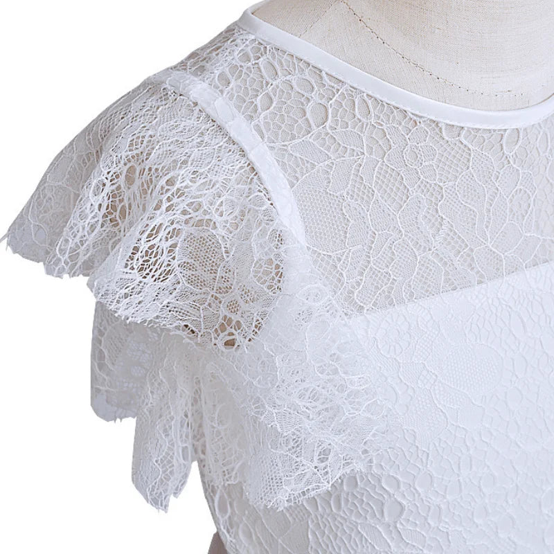 Détail des finitions en dentelle sur l'épaule d'une robe de fête pour enfant.