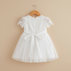 Vue de dos de la robe de baptême montrant la ceinture en satin à nouer et le jupon en voile