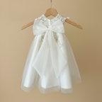 Détail du dos de la robe de baptême sur cintre avec son imposant nœud papillon en tulle blanc