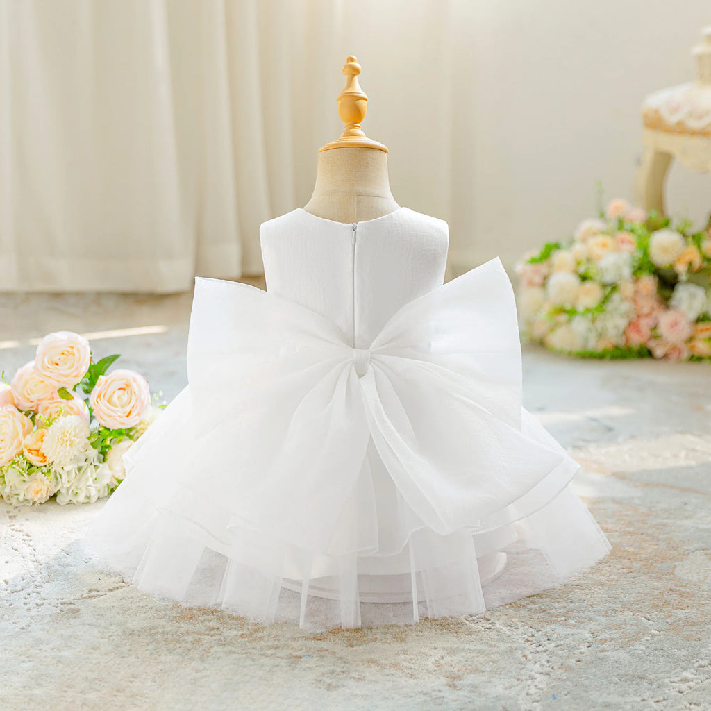 Vue arrière de la robe de cérémonie blanche pour bébé avec son grand nœud.
