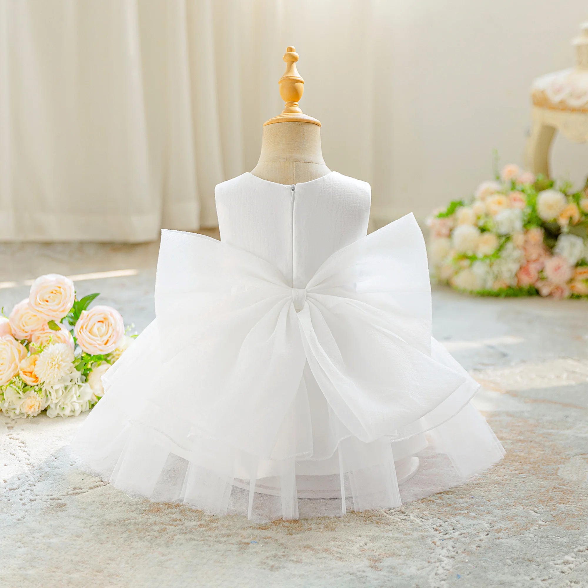 Vue arrière de la robe de cérémonie blanche pour bébé avec son grand nœud.