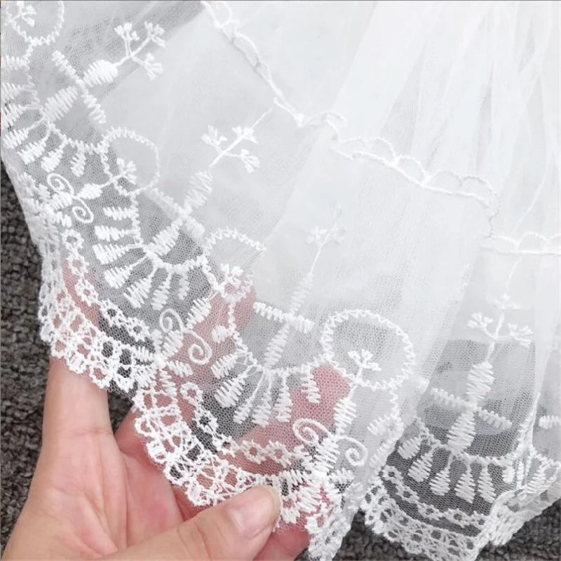 Détail de la bordure en dentelle brodée sur le bas d'une robe de baptême pour petite fille