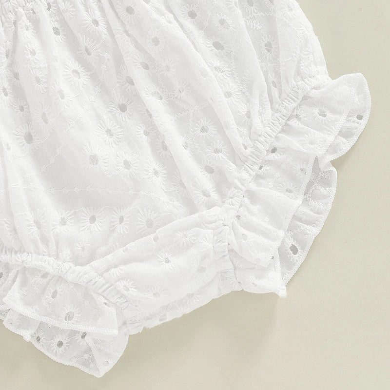 Zoom sur les finitions dentelées et le bas évasé d'une robe de baptême blanche