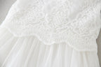 Détail de la jonction entre le bustier en dentelle et la jupe en tulle de la robe de baptême