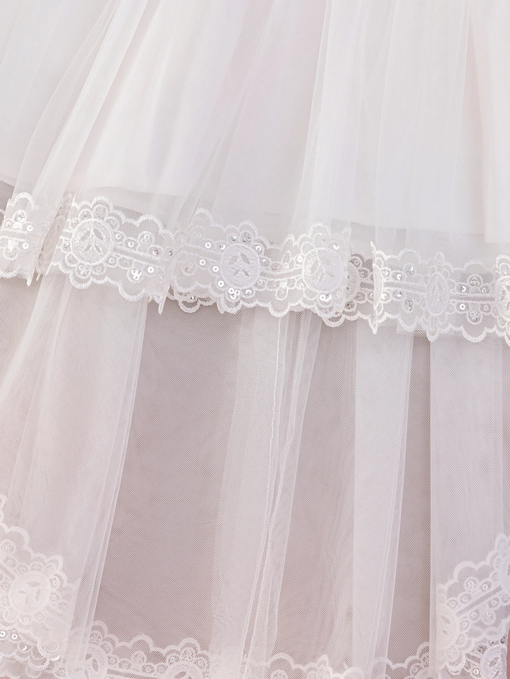 Détail des épaisseurs de tulle vaporeux et de la finition bordée de dentelle fine sur le bas de la robe