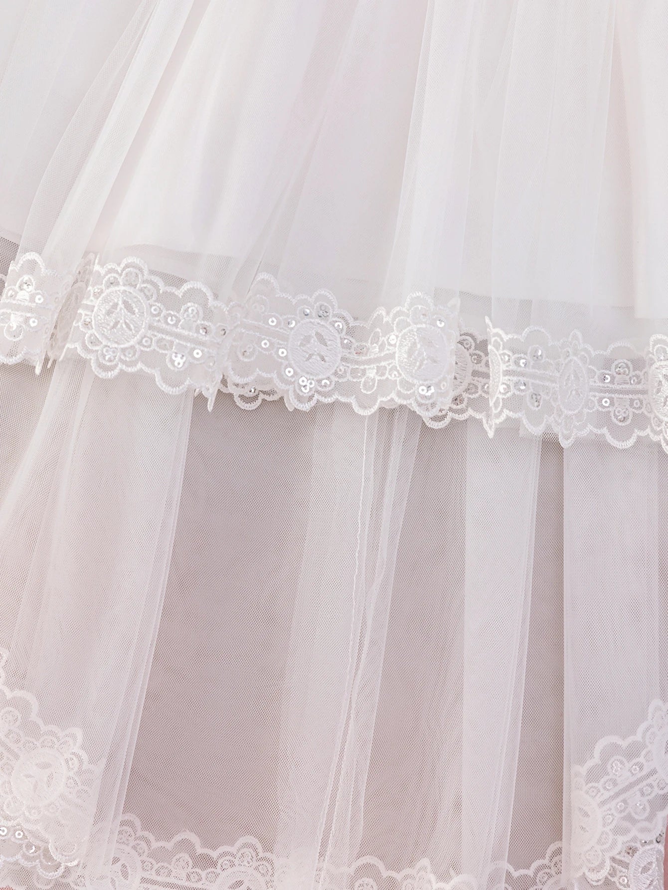 Détail des épaisseurs de tulle vaporeux et de la finition bordée de dentelle fine sur le bas de la robe