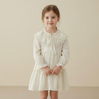 Petite fille portant la robe bohème en coton crème avec col volanté en dentelle