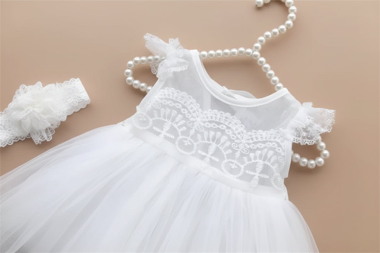 Robe de cérémonie blanche pour bébé présentée sur un cintre avec son bandeau à fleurs