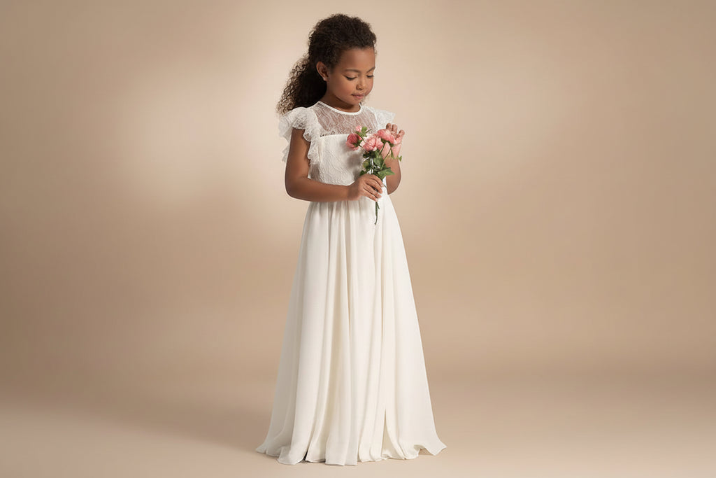 Petite fille portant une robe de cérémonie bohème longue blanche avec bouquet de fleurs.