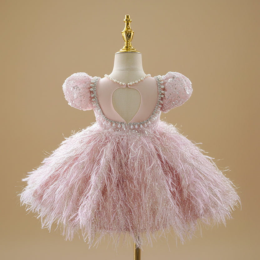 Vue arrière de la robe de cérémonie rose montrant le volume de la jupe à plumes.