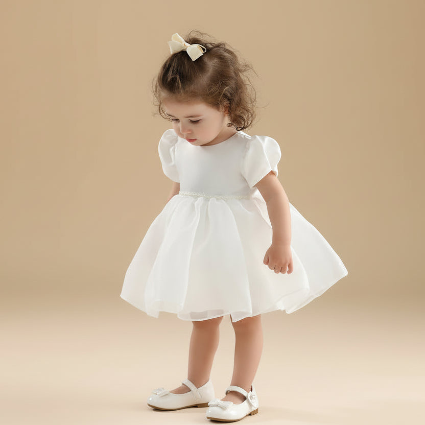 Petite fille portant la robe de cérémonie Coralie blanche avec manches bouffantes et jupe volumineuse