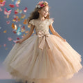 Petite fille portant la robe de gala longue Lucia couleur champagne avec bustier pailleté et jupe volumineuse