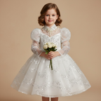 Petite fille portant la robe de princesse Juliana blanche ornée de sequins avec manches bouffantes et bouquet