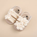 Paire de sandales souples pour bébé couleur beige avec deux grandes fleurs en tissu ornées d'une perle centrale et détails en crochet