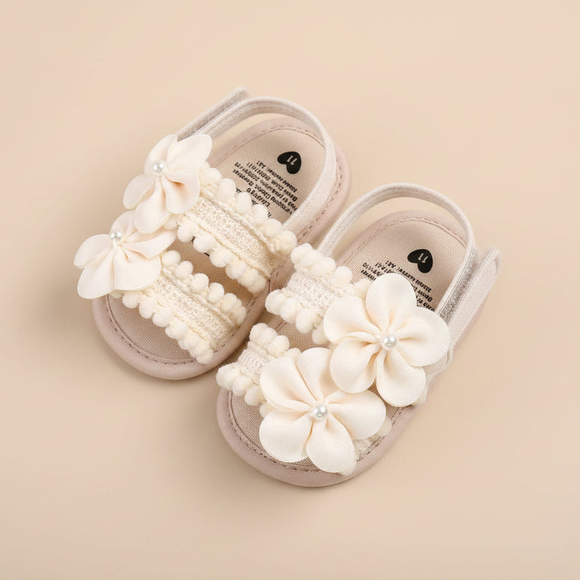 Paire de sandales souples pour bébé couleur beige avec deux grandes fleurs en tissu ornées d'une perle centrale et détails en crochet