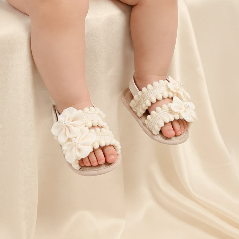 Sandales de cérémonie beige portées par un bébé, montrant le rendu élégant des fleurs sur le pied