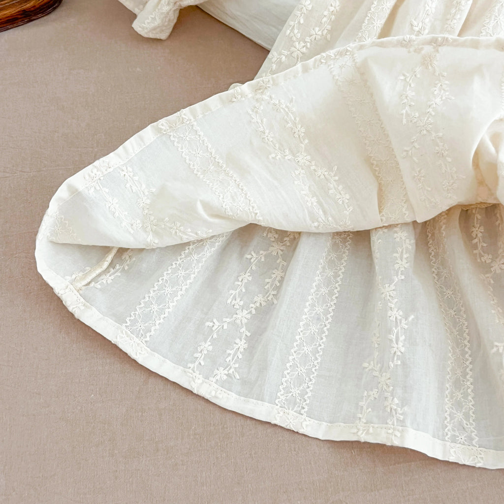 Gros plan sur le tissu en coton texturé et les broderies du bas de la robe