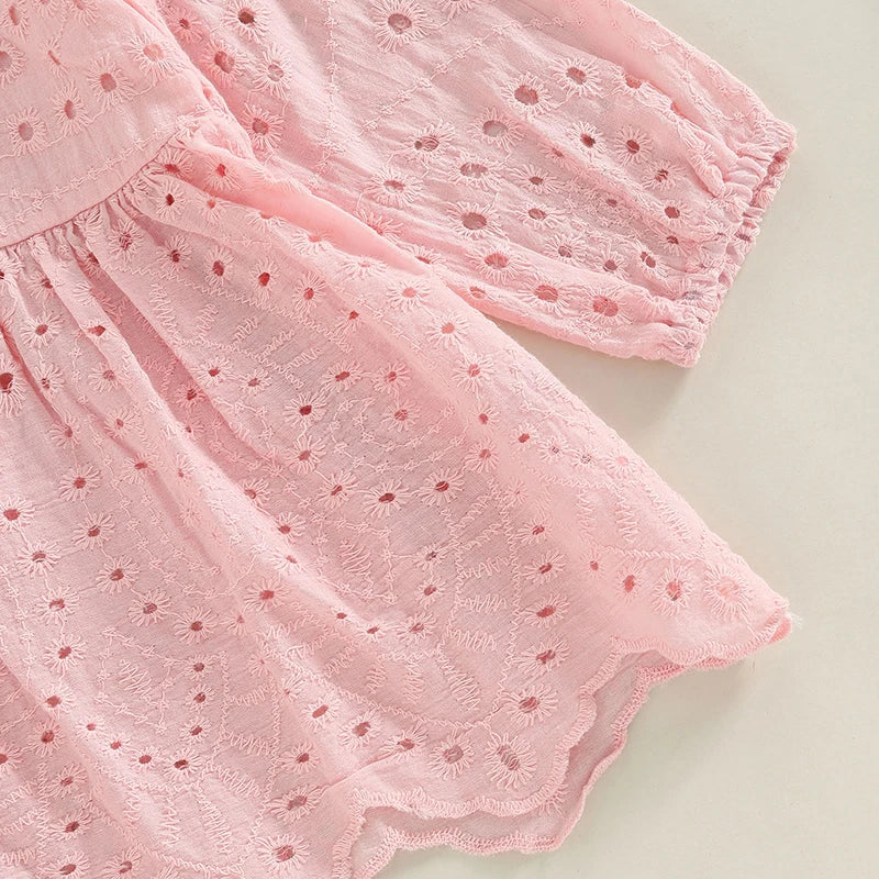 Détail de la texture du tissu en coton rose et des motifs de broderie pour robe bébé