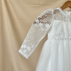 Gros plan sur la manche transparente en tulle ornée de motifs floraux en dentelle blanche