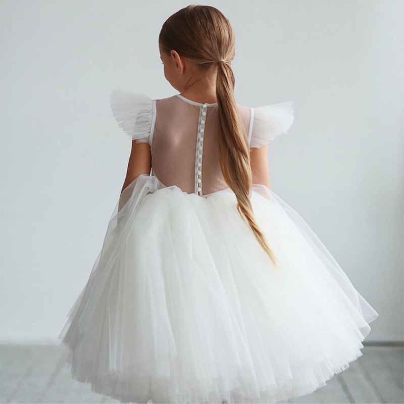 Vue de dos de la robe de cérémonie montrant le dos transparent boutonné et le jupon en tulle