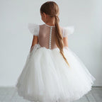 Vue de dos de la robe de cérémonie montrant le dos transparent boutonné et le jupon en tulle